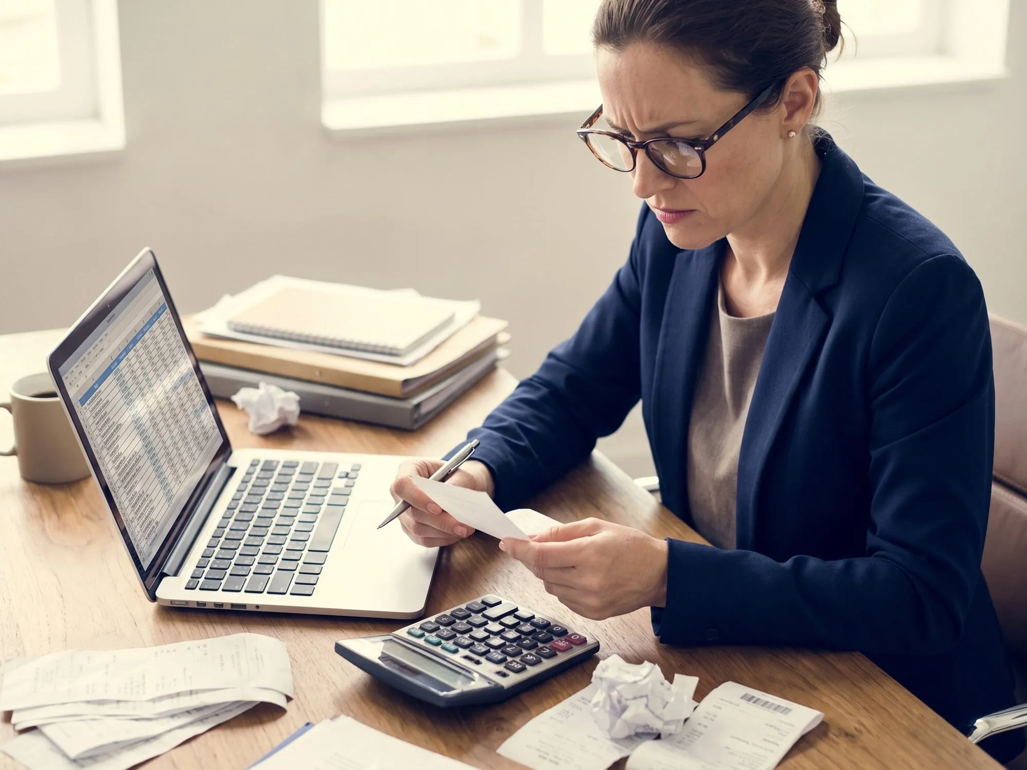 Geschäftsfrau prüft Finanzbelege mit Stift am Büroschreibtisch