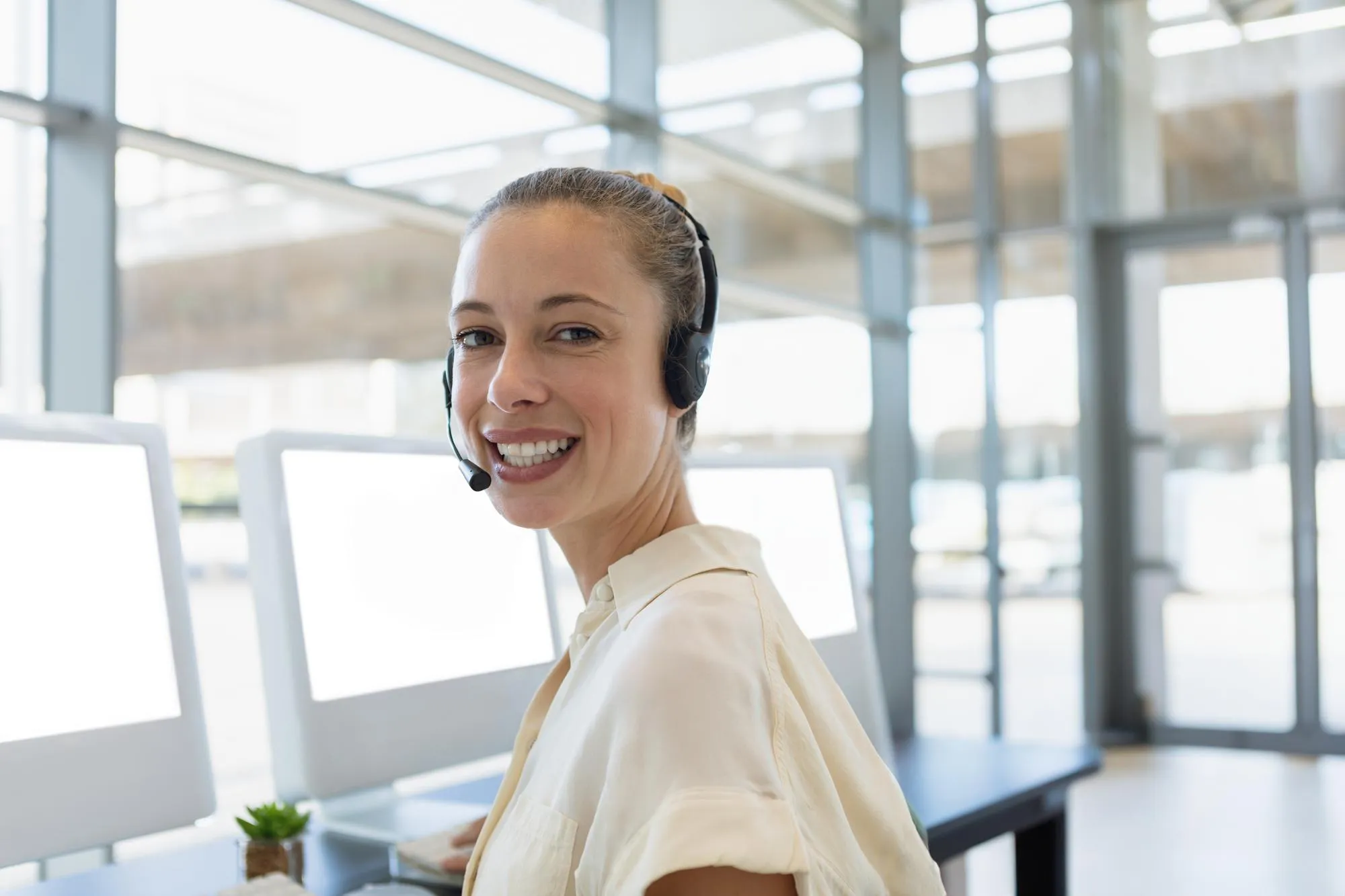 Mitarbeiterin mit Headset am Arbeitsplatz: Cloud-Telefonie im Arbeitsalltag