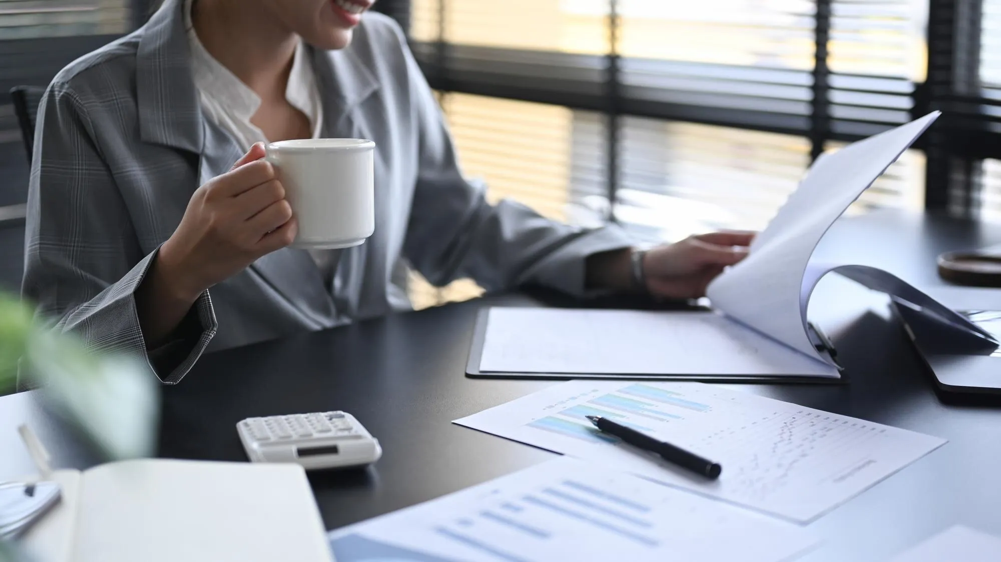 Managerin prüft Finanzberichte und Kosten am Laptop im hellen, modernen Büro
