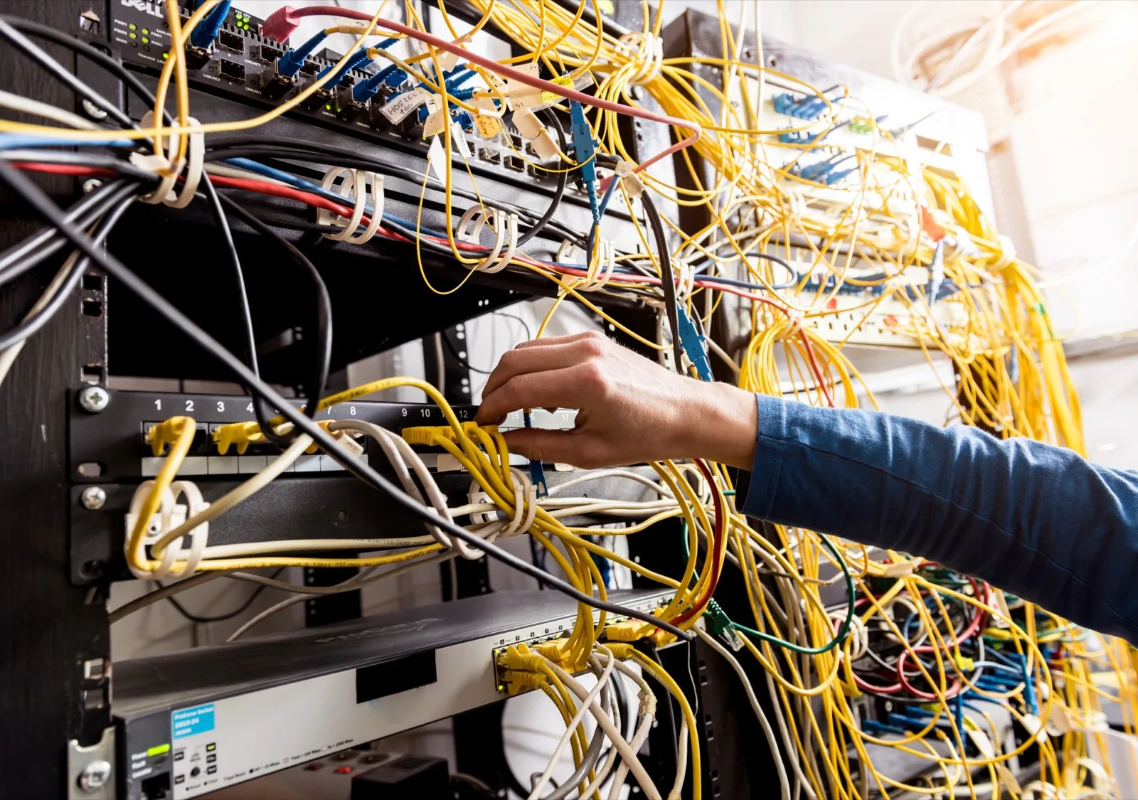 Hand steckt Netzwerkkabel an einem Server-Rack um