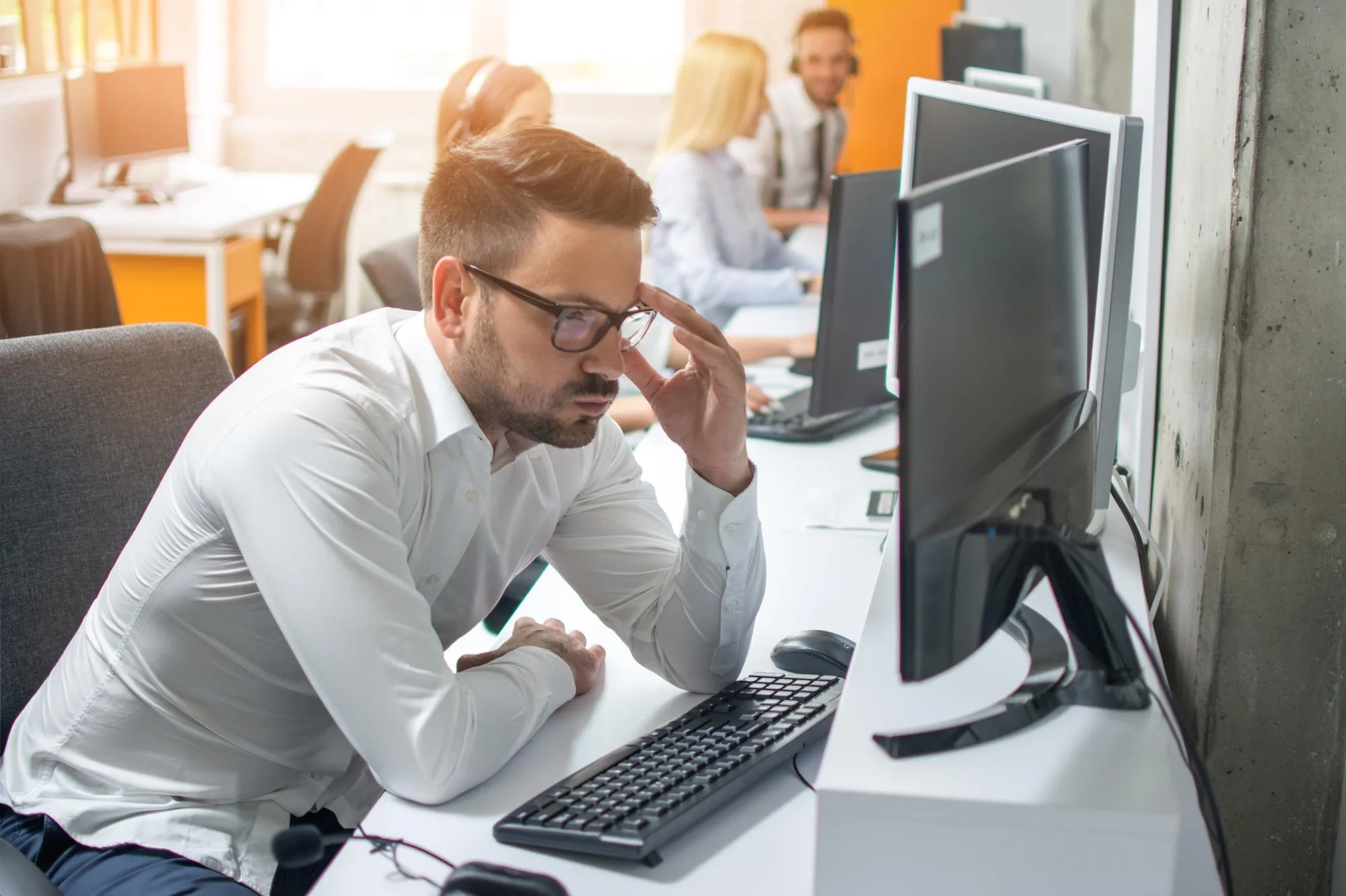 Angespannter Mitarbeiter blickt konzentriert auf den Bildschirm im Büro