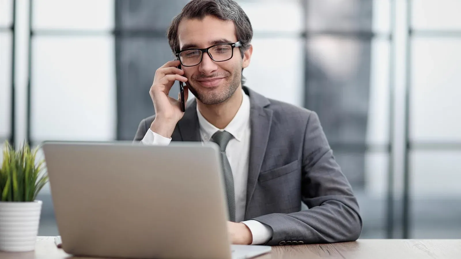 Sales Development Representative im Kundentelefonat, Laptop am Arbeitsplatz