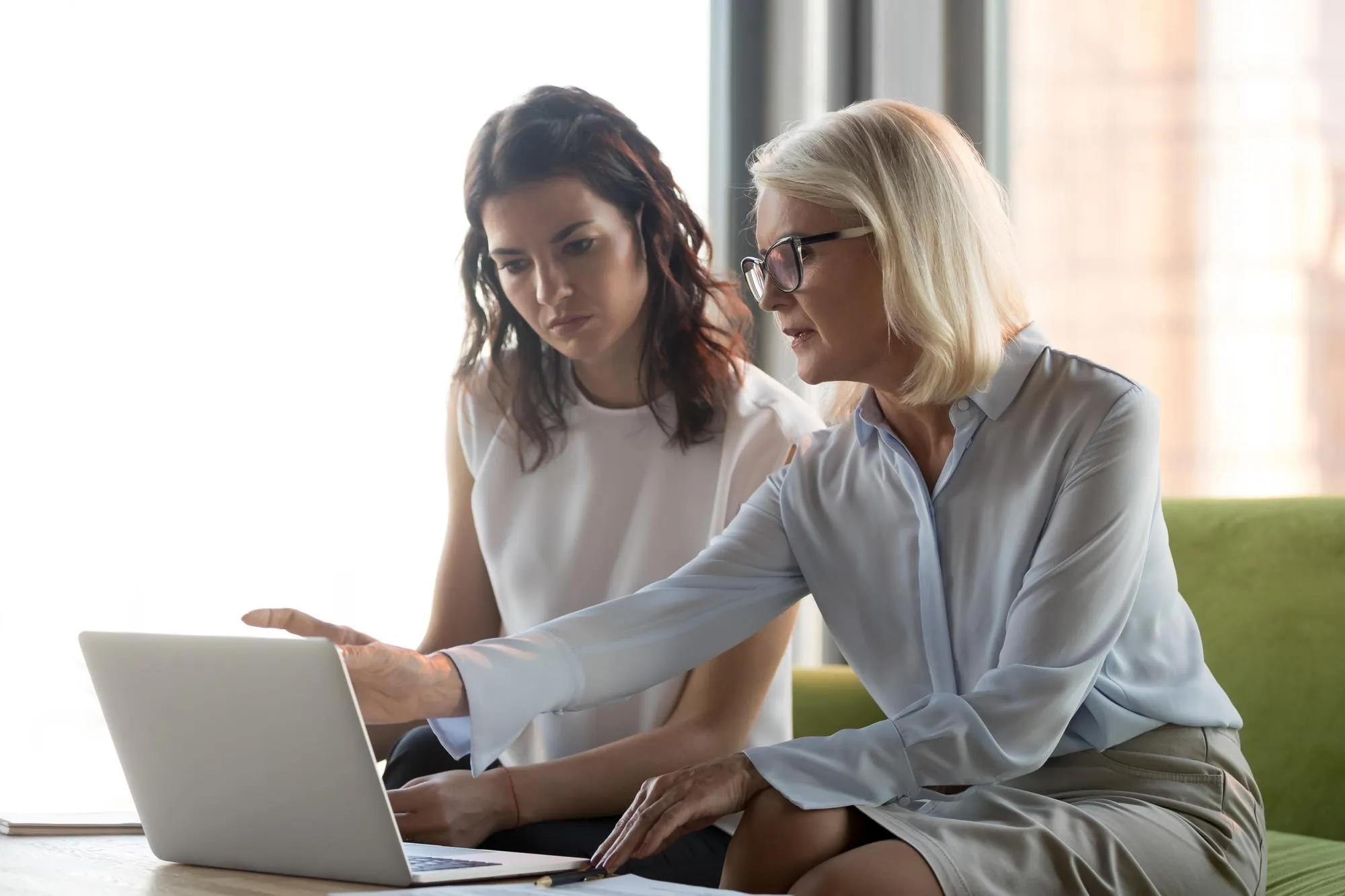 Beraterin erklärt einer Kundin am Laptop partnerschaftlich das weitere Vorgehen